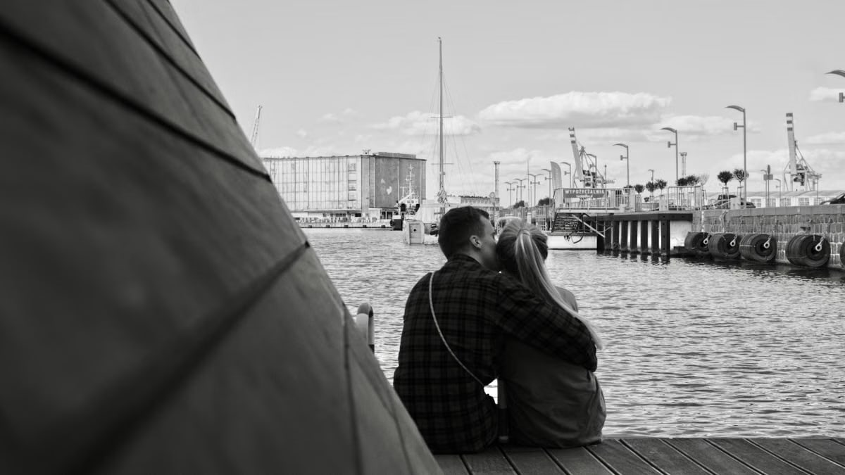 A couple embraces by the harbor in Wrocław, Poland. Monochrome image capturing a serene moment by the water.
