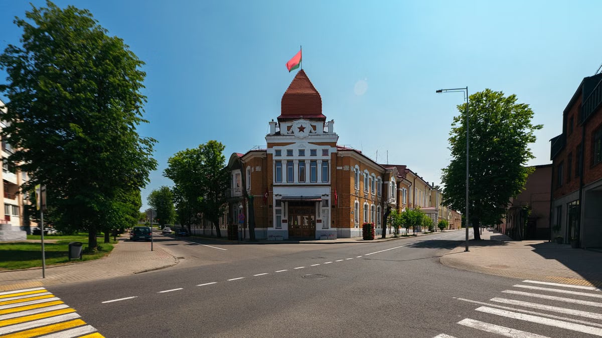 An empty street featuring a historic building with a red flag under a clear sky.